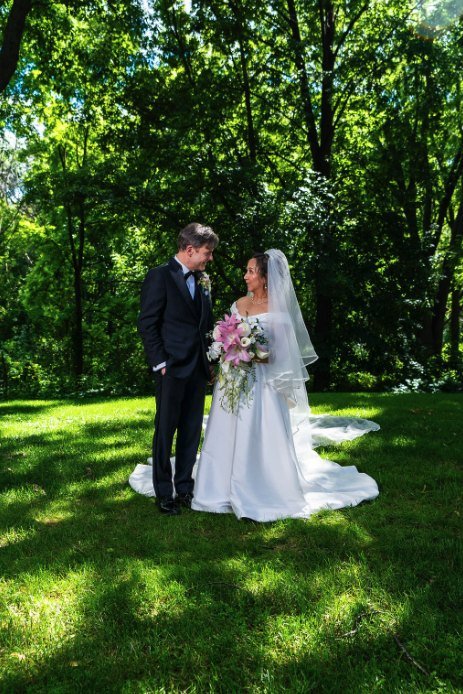 Los novios mirándose entre los árboles, con el ramo de lilis