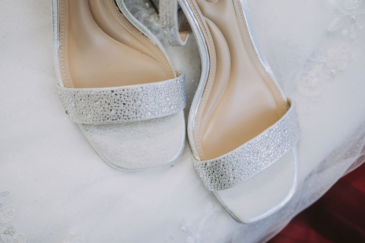 Zapatos plateados de la novia sobre el velo de encaje