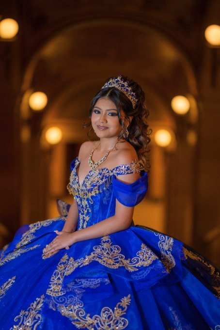 Retrato cercano de la quinceañera con corona y vestido azul bordado en dorado