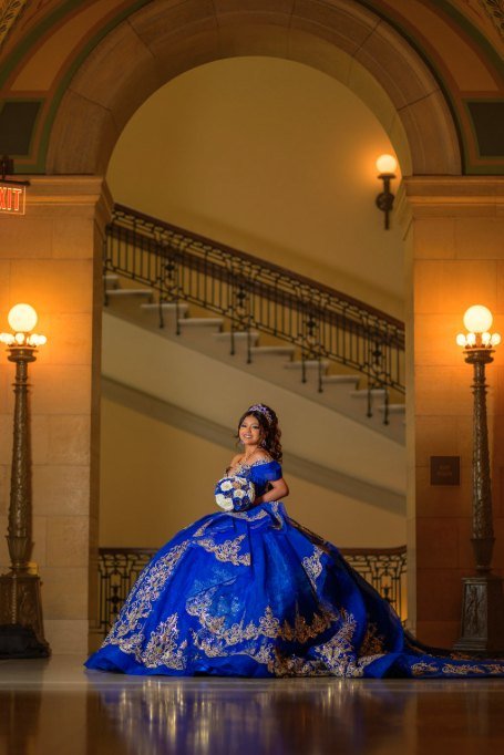 Quinceañera frente a la escalinata, bajo los faroles del vestíbulo