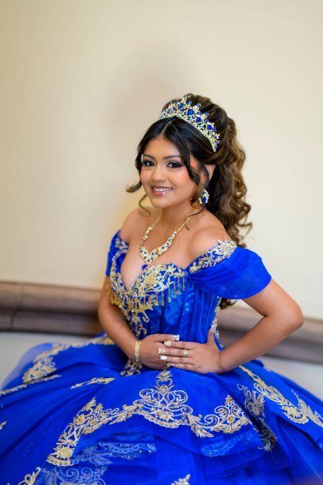 Quinceañera sentada, sonriendo, con el vestido azul desplegado
