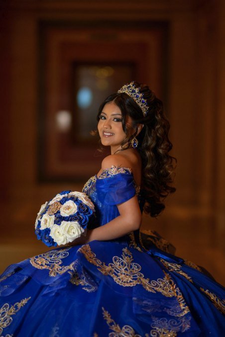Quinceañera de perfil sosteniendo el ramo de rosas blancas y azules