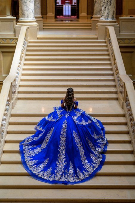 Quinceañera de espaldas subiendo la escalinata de mármol